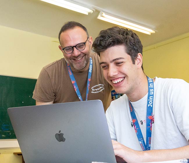 A teacher and student working together on a Macbook